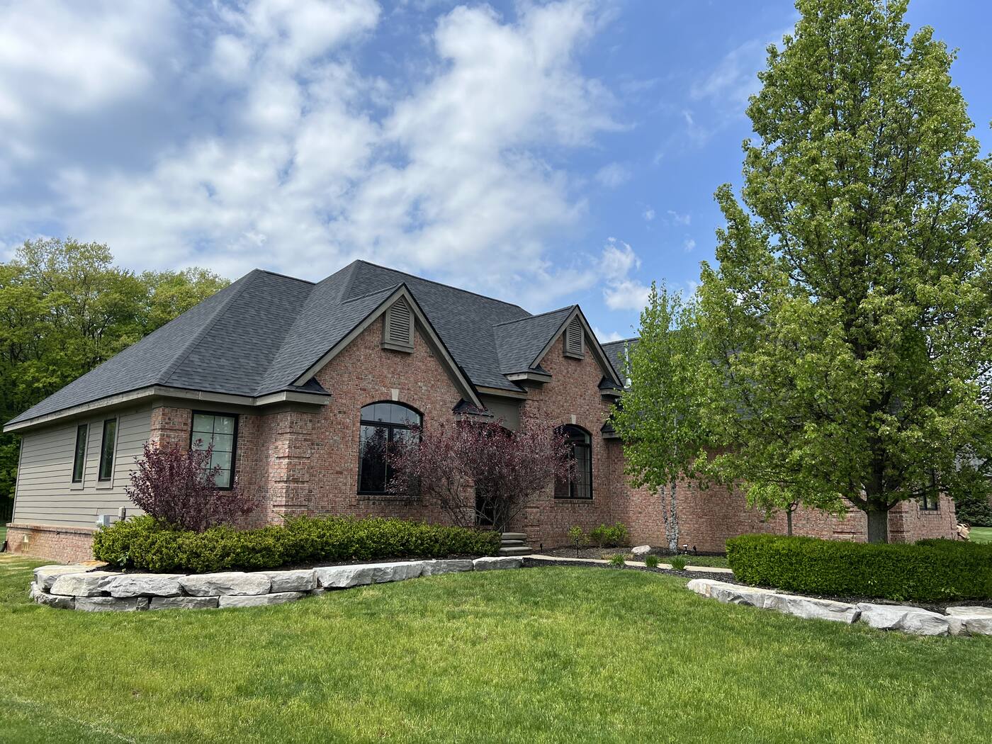 New roof on a brick estate home with multiple gables and dormers