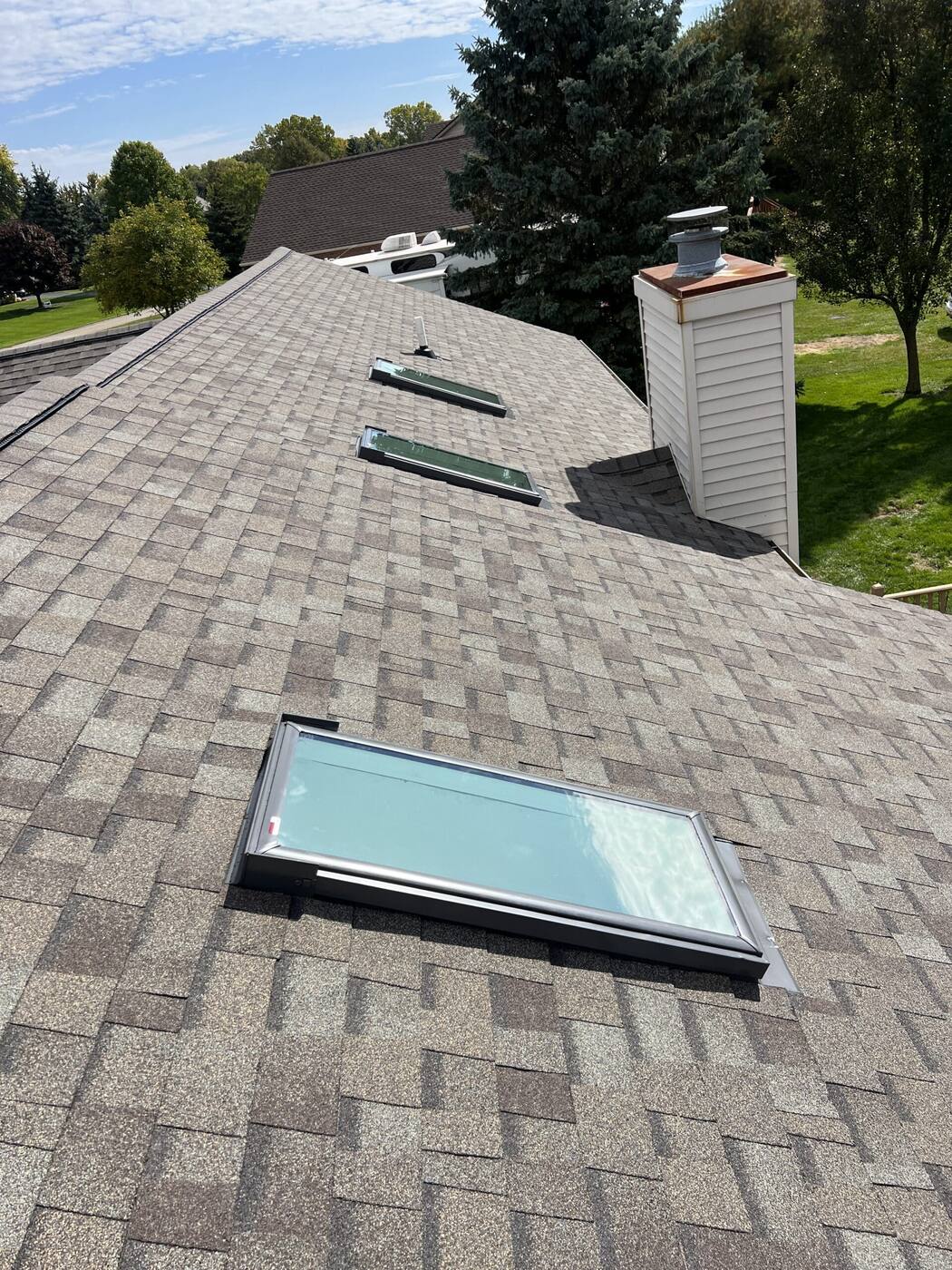 Skylights and chimney integrated into a finished shingle roof